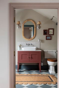 a bathroom with a toilet, sink and mirror in it's doorway way to another room