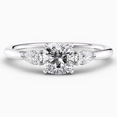 a diamond engagement ring with three stones on the band and an oval shaped center stone