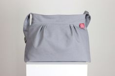 a gray bag sitting on top of a white box with a red tag hanging from it's side