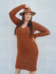 a woman standing in front of a brick wall wearing a brown knitted dress and hat