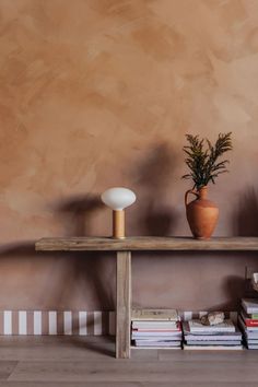 a wooden table topped with a potted plant next to books and a lamp on top of it