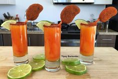 three glasses filled with orange liquid and limes