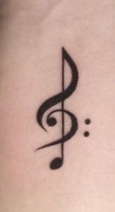 a musical note tattoo on the back of a woman's stomach, with black ink