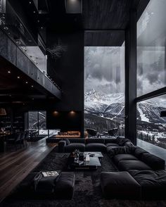 a living room filled with lots of black furniture and large windows overlooking the mountain range