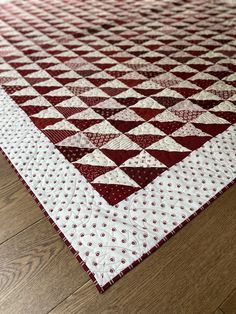 a red and white quilted area rug on the floor in a room with wood floors