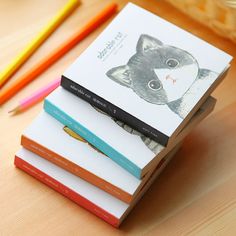 a stack of three books sitting on top of a wooden table next to colored pencils