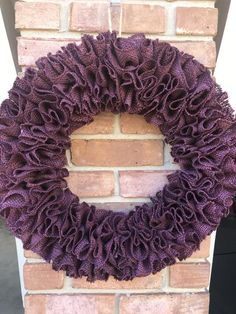 a purple wreath hanging on the side of a brick wall