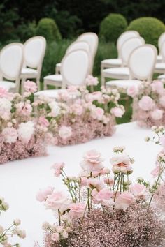 rows of white chairs with pink flowers on them