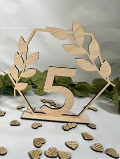 the number five is made out of wood and surrounded by small wooden heart shaped leaves