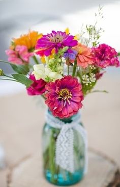 a vase filled with colorful flowers sitting on top of a wooden table next to a tree stump