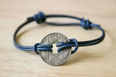 a bracelet with a coin on it sitting on top of a wooden table