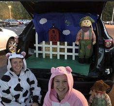 two women sitting in the back of a car with stuffed animals on it's trunk