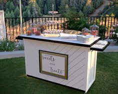 a buffet table with food on it in the middle of a field near a fence