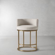 a white and gold bar stool with a round seat on the bottom, in front of a gray wall