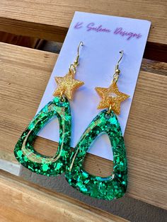 green and gold earrings with stars on them sitting on top of a piece of paper