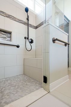 a bathroom with a glass shower door and tile flooring, along with white walls