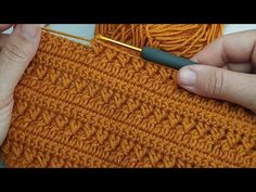 someone crocheting the stitches on an orange sweater