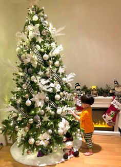 a little boy standing next to a christmas tree