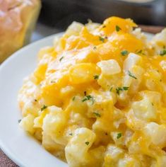 scrambled eggs on a white plate with bread in the background