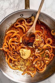 the food is being cooked in the pan on the stove top with a wooden spoon