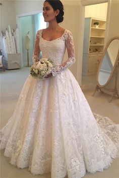 a woman in a white wedding dress standing next to a mirror and looking at the camera