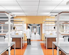 a man in white lab coat standing at the end of an orange and white hallway