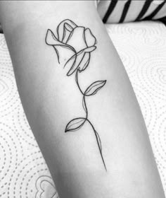 a black and white photo of a single rose tattoo