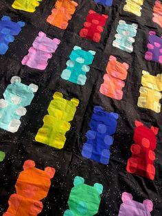 a black quilt with multicolored teddy bears on it's back and sides