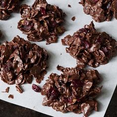 chocolate cookies with cranberries and nuts on a piece of parchment paper, ready to be eaten