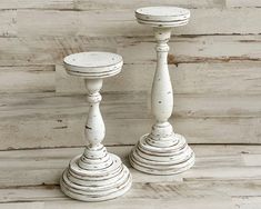 two white candlesticks sitting on top of a wooden floor next to each other