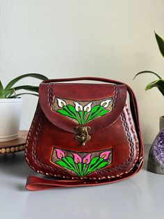 Beautiful, embossed, genuine leather hand tooled floral purse, skillfully made by Artisans in Mexico using the "cincelada" technique. Latch Closure and adjustable strap. Includes a storage bag to protect your purse when not in use.  Dimensions: 11" L x 4" W x 10'' H. Tapered at the top to create a truly unique style. Please check measurements if you have any concerns about sizing before purchase. Includes a dust bag as pictured, to protect your purse when not in use. Imported from Mexico, they a Traditional Leather Saddle Bag, Artisan Hand Painted Brown Bags, Traditional Hand Tooled Saddle Bag, Traditional Hand Tooled Shoulder Bag As A Gift, Artisan Hand Tooled Saddle Satchel Bag, Traditional Hand Tooled Bags For Everyday Use, Traditional Hand-tooled Bags For Everyday Use, Traditional Hand Tooled Bags, Traditional Handmade Leather Satchel