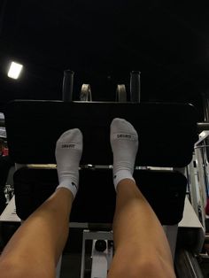 the legs of a person who is standing on a weight machine