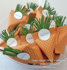 orange and white paper flowers in a bowl with name tags on the top for each flower