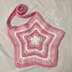 a pink and white crocheted bag on a bed