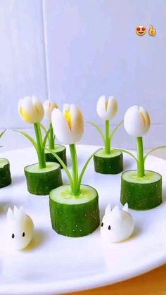 cucumber slices and flowers are arranged on a white platter with small plastic rabbits