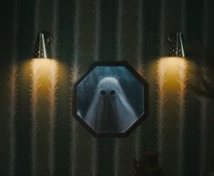 two lights are on in front of a mirror that has a ghost image on it