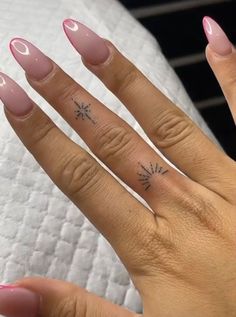 a woman's hand with pink nail polish and stars on her ring finger tattoo