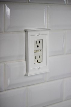 an electrical outlet on the wall with white tiles in the backgroung area