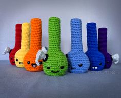 six crocheted colorful vases with faces on them, all lined up in a row