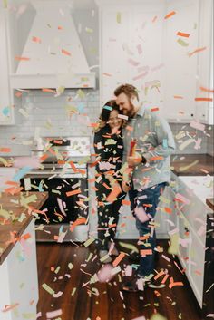 a man and woman standing in a kitchen surrounded by confetti