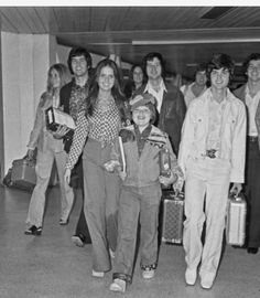 black and white photograph of people walking through an airport with suitcases in their hands