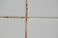 the corner of a white tile wall with peeling paint on it and a rusted edge