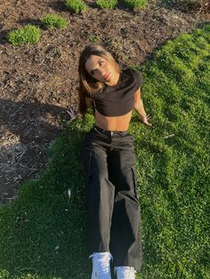 a woman laying on the grass with her legs crossed and headphones in her ears