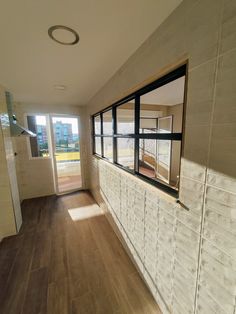 an empty room with wooden floors and large windows on the wall, looking out onto a grassy field