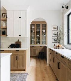 a large kitchen with wooden cabinets and white counter tops, along with an arched doorway leading to the dining room