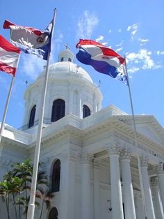 three flags flying in front of a white building