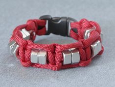 a red and silver bracelet with metal clasps on a gray background, close up