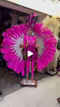 a woman in pink and silver costume standing on top of a skateboard with wings