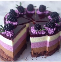 there is a cake with purple and blackberries on the top it has one slice cut out