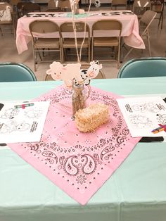 a table set up for a party with pink napkins and paper decorations on it